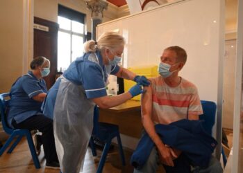 PENDUDUK menerima suntikan vaksin AstraZeneca di pusat vaksinasi sementara yang ditubuhkan di Dewan Bandaraya di Hull, timur laut England pada 7 Mei lalu. - AFP