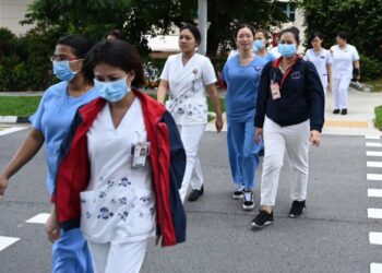 BEBERAPA kakitangan perubatan berjalan ke bangunan Pusat Nasional bagi Penyakit Berjangkit (NCID) di Hospital Tan Tock Seng di Singapura. - AFP