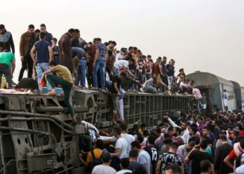 ORANG ramai memanjat gerabak kereta api yang tergelincir bagi membantu mengeluarkan mangsa di Banha, Qalyubia, Mesir. - AFP