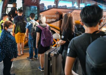 ORANG ramai menaiki bas di Singapura untuk masuk ke Malaysia menerusi VTL darat. - AFP