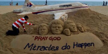 SEORANG artis menyiapkan binaan pasir yang mendoakan kesejahteraan pesawat MH370 di tepi pantai di Puri, India. - AFP