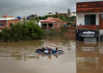 DUA penduduk menggunakan tilam angin untuk bergerak dalam kawasan yang dinaiki banjir di Itapetinga, Bahia, Brazil. - AFP