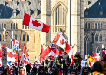 PENUNJUK perasaan mengibarkan bendera Kanada ketika berkumpul berhampiran perkarangan Parlimen di Ottawa. - AFP