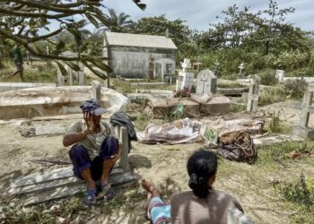 PENDUDUK setempat duduk di sebelah mayat keluarga mereka yang 'terkeluar' dari kubur akibat hakisan ombak yang disebabkan Siklon Batsirai di Madagascar. - AFP