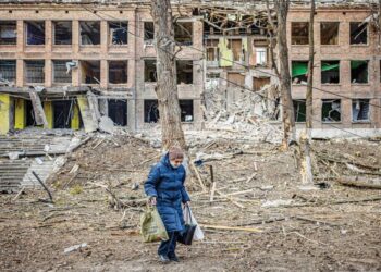 SEORANG wanita berjalan melintasi bangunan musnah akibat serangan peluru berpandu Rusia di pekan Vasylkiv, berhampiran Kyiv, Ukraine. - AFP