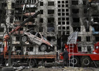 SEBUAH kren mengalihkan kereta rosak di hadapan pangsapuri yang musnah akibat serangan di daerah Obolon barat laut Kyiv, Ukraine. - AFP