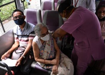 PETUGAS kesihatan memberikan suntikan vaksin Covishield kepada warga emas di dalam bas di Kolkata. - AFP