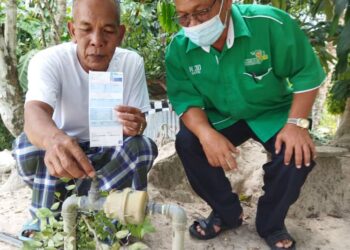 MOHD. Zukri Nen (kanan) menunjukkan bil air yang terpaksa dibayar setiap bulan walaupun tidak mendapat bekalan air daripada SADA di Kampung Tanjung Pari, Mukim Siong, semalam.