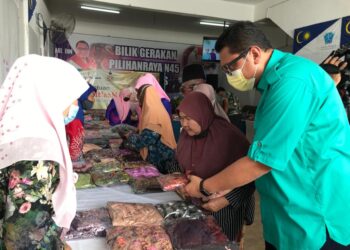 MOHD. Syahbuddin Hashim membantu ibu tunggal memilih pakaian raya di Bandar Utama, Gua Musang, Kelantan, hari ini. - UTUSAN/AIMUNI TUAN LAH