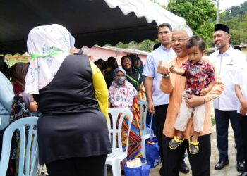 Al-Sultan Abdullah Ri’ayatuddin Al-Mustafa Billah Shah mendukung seorang kanak-kanak sambil beramah mesra dengan penduduk ketika melawat Kampung Orang Asli Kuala Boh di  Cameron Highlands hari ini. - UTUSAN/ZULFACHRI ZULKIFLI