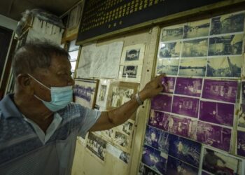 CHA Bong Kuan menunjukkan gambar-gambar lama kejadian air laut pasang besar yang pernah melanda pada tahun 1999 dan menenggelamkan rumahnya ketika fenomena itu melanda Pantai Barat Semenanjung sejak Khamis lalu di Pulau Ketam, Klang Selangor, hari ini. - FOTO/FARIZ RUSADIO