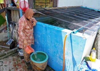 Sharifah Fajariah Syed Aman, 71, menggunakan air hujan yang ditadah dalam takungan besar untuk kegunaan harian berikutan ketiadaan kemudahan asas termasuk elektrik dan jalan raya di Kampung Melayu Bukit Tarek, Hulu Selangor sejak 30 tahun lalu. – UTUSAN/SHIDDIEQIIN ZON