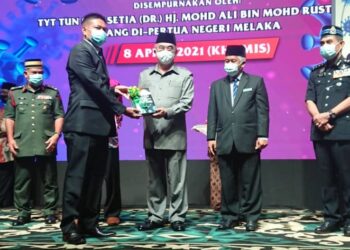 MOHD. ALI Mohd. Rustam (tengah) menerima buku Covid-19 Melanda Negara dan Dunia di Hotel Muzaffar Ayer Keroh, Melaka. - UTUSAN/DIYANATUL ATIQAH ZAKARYA