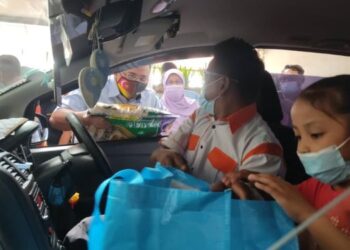 AMIRUDIN Shari menyerahkan sumbangan bakul makanan kepada salah seorang pemandu teksi sambil diperhatikan oleh Rodziah Ismail (dua dari kiri) sempena majlis pengagihan bakul makanan kepada pemandu teksi dan bas di Bangunan SUK Selangor hari ini. -  FOTO/NORHAYATI YAHAYA