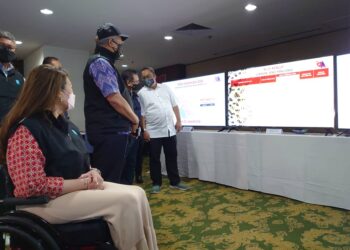 ANNUAR Musa (berdiri, bertopi) melihat maklumat yang dipaparkan di Pusat Media PRN Johor di Hotel Grand Paragon, Johor Bahru, hari ini.