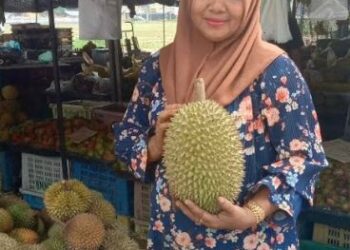 1)	Arisah Long  menunjukkan `Raja Buah’, durian, yang merupakan antara  buah-buahan dijual di kedainya.