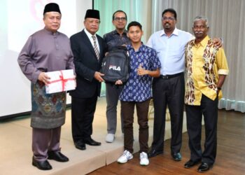 NUR Ameer Muqsiq  (tengah) menerima cenderahati pada majlis sambutan Hari Raya Aidilfitri Akademi Hoki AHF Raja Ashman Shah di Ipoh semalam. - UTUSAN/MUHAMAD NAZREEN SYAH MUSTHAFA