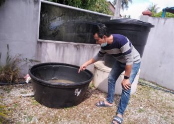 NORHISHAM Mohd Kasim menunjukkan tangki kering di rumahnya di Taman Bina Raya 2 kerana terputus bekalan sejak dua minggu lalu. - UTUSAN/ROHANA MOHD.NAWI