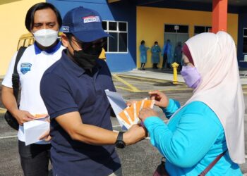 NOOR Azleen Ambros (bertopi) menyampaikan baucer minyak percuma kepada salah seorang pemandu van sekolah ketika menghadiri Program Sanitasi Bas dan Van Sekolah dan Baucer Minyak Percuma di Dewan Serbaguna Taman Scientex, Pasir Gudang di Johor. -UTUSAN/RAJA JAAFAR ALI