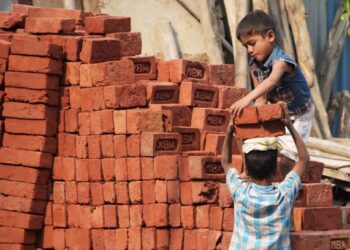 GAMBAR bertarikh 19 November 2017 menunjukkan dua kanak-kanak menyusun bata di tapak pembinaan di New Delhi, India. - AFP