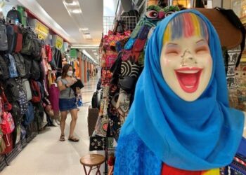 SEORANG wanita memakai pelitup muka ketika berjalan di kedai yang tiada pelanggan di Bangkok. - AFP