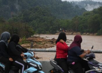 PENDUDUK melihat kesan kayu yang hanyut disebabkan kepala air ketika tinjauan di Kampung Belukar Bukit, Terengganu, semalam. - UTUSAN/PUQTRA HAIRRY