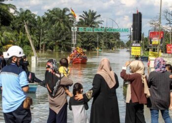 Ahli keluarga dan mangsa banjir melihat keadaan air yang masih belum surut menyukarkan penduduk untuk pulang ke rumah mereka di RTB Bukit Changgang, Kuala Langat hari ini. - UTUSAN/FAISOL MUSTAFA