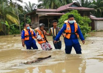 ANGGOTA APM membantu wanita mangsa banjir (dua dari kiri) berpindah dari rumahnya di Kampung Chikus di Teluk Intan, Perak hari ini. - FOTO/AIN SAFRE BIDIN