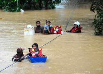 ANGGOTA bomba membantu memindahkan  tiga kanak-kanak dan seorang wanita selepas rumah mereka dinaiki air di Kampung Sentosa Masai, Pasir Gudang, Johor. - UTUSAN/RAJA JAAFAR ALI