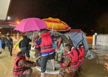 ANGGOTA bomba memindahkan mangsa banjir di Kampung Sumpitan, Lenggong, Ipoh, hari ini. - FOTO/IHSAN JBPM