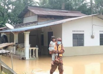 ANGGOTA bomba mendukung seorang kanak-kanak untuk berpindah ke PPS setelah rumahnya dinaiki air di Raub, Pahang. - IHSAN BOMBA