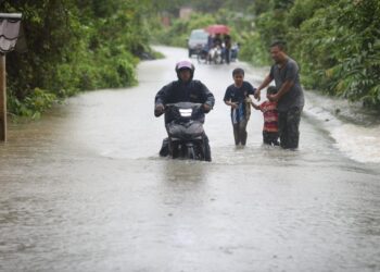 PENDUDUK meredah jalan yang dinaiki air di Kampung Titian Baru, Marang, Terengganu. - UTUSAN/PUQTRA HAIRRY ROSLI