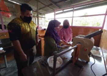 SHARIFAH Azizah Syed Zain (dua kiri) mencuba menyiapkan produk makanan ketika melakukan lawatan dan penyerahan sijil PKPJ kepada tiga usahawan di Felda Sungai Mas, Felda Semenchu dan Felda Air Tawar 1 di Kota Tinggi, Johor. -UTUSAN/MASTURAH SURADI