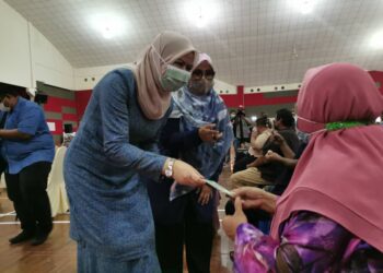 RINA Mohd. Harun (kiri) menyampaikan sumbangan duit raya kepada penerima makanan Bakul Permai  di Kolej Kemahiran Tinggi Melaka, Paya Lebar, Melaka. - UTUSAN/DIYANATUL ATIQAH ZAKARYA