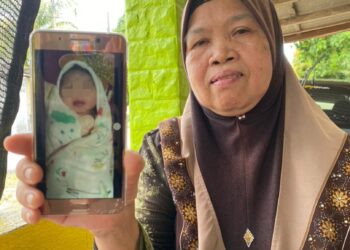 SALEMAH Awang menunjukkan gambar bayi yang dijumpai dibuang di belakang rumahnya di Kampung Geliga, Kemaman hari ini.
\