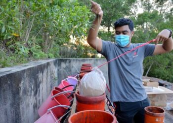 PEKERJA Proteknik Red Flame Special Effects Sdn. Bhd., Mohd. Syahiran Shafie memasukkan bahan peledak bunga api ke dalam lubang khas yang akan diletupkan untuk menandakan masuk waktu berbuka puasa di Puncak Panorama, Bukit Pak Apil, Kuala Terengganu, baru-baru ini. – UTUSAN/PUQTRA HAIRRY ROSLI