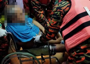 ANGGOTA bomba membantu memindahkan mangsa banjir OKU dalam kejadian di Kampung Melayu Raya, Pekan Nanas, Pontian malam tasi.