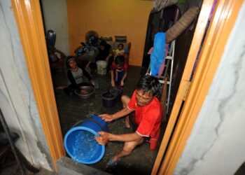 FAUZI Kassim bersama anak-anak membuang air yang memasuki rumahnya akibat banjir berikutan hujan lebat lebih dua jam di Kampung Pasir, Tampoi di Johor. - UTUSAN/RAJA JAAFAR ALI