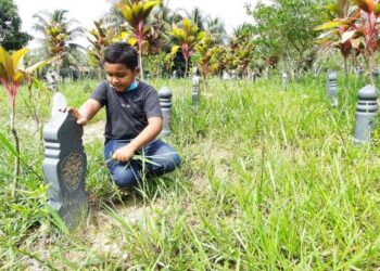 MUHAMMAD Haziq Zikri membersihkan pusara ibunya, Noratiqah Abd. Hamid di Tanah Perkuburan Islam Kampung Badlishah, Serdang, Kulim, semalam.