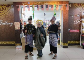 MAIMUNAH Madlan (tengah) bersama dua peniaga Galeri Warisan di Banda Hilir, Melaka mengenakan busana tradisional sempena sambutan Hari Malaysia. - UTUSAN/MUHAMMAD SHAHIZAM TAZALI