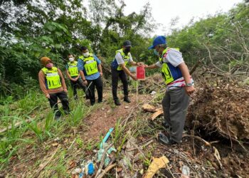 ISMASUHAIMI Shariff (dua dari kanan) menampal Notis 8A di salah sebuah lot tanah yang dirampas susulan kegagalan menjelaskan bayaran tunggakan cukai di sekitar kawasan Chuping, Padang Besar, Perlis, hari ini. -UTUSAN/ASYRAF MUHAMMAD