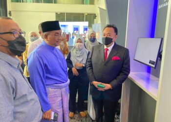 MUHAMMAD Sanusi Md. Nor (tengah) melihat sistem pembayaran tanpa tunai dan iHasil Kedah di Pejabat Tanah Kota Setar di Alor Setar, hari ini.