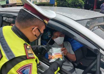 KETUA Polis Trafik Bandar Lampung, Rafly Yusuf Nugraha memberikan multivitamin kepada pengguna jalan raya dalam Operasi Lilin Krakatau 2020. - KOMPAS.COM