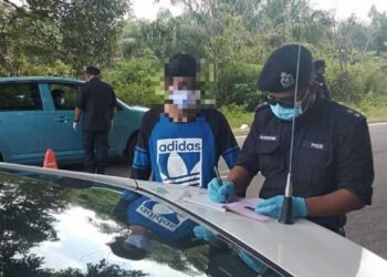 SEORANG anggota polis mengeluarkan kompaun kepada seorang lelaki yang didapati cuba merentas negeri dari Keratong, Pahang ke Bandar Seri Jempol, Jempol, Negeri Sembilan, tengah hari tadi. - IHSAN POLIS