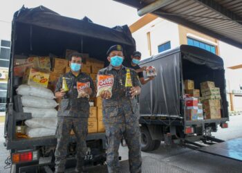 MOHD. Khairi Abdullah (depan) menunjukkan sebahagian makanan dan minuman seludup yang dirampas di Bukit Kayu Hitam, Kubang Pasu, hari ini. - UTUSAN/SHAHIR NOORDIN