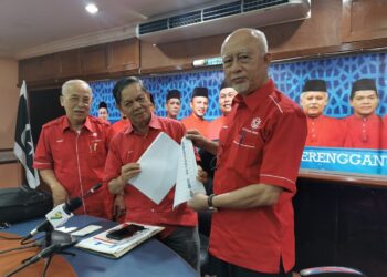 MUSTAPHA Yaakub (kanan) menunjukkan borang senarai nama calon-calon yang akan bertanding dalam pemilihan parti selepas taklimat khas di bangunan UMNO Negeri di Kuala Terengganu, hari ini. - UTUSAN/KAMALIZA KAMARUDDIN