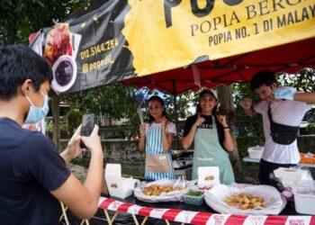 TIGA beradik, Afiera Riana Agoes Riauwaldy (tengah), Afiefi Riani (kiri) dan Ahmad Amin (kanan) sempat menari ketika menunggu pelanggan untuk dimuat naik ke aplikasi TikTok  bagi tujuan mempromosikan perniagaan mereka di Taman Kosas, Ampang, Selangor, baru-baru ini. – UTUSAN/MUHAMAD IQBAL ROSLI