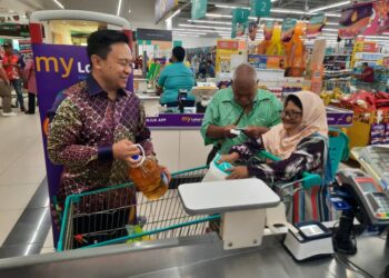 WAN Saiful Wan Jan (kiri) menyampaikan barangan keperluan dapur kepada pasangan suami isteri dalam Program MyKasih Foundation di sebuah pasar raya di Jitra, hari ini. -UTUSAN/MOHD. RIFAAT ABD HAMID