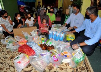 MAS Imran Adam (dua dari kanan) menyampaikan sumbangan barangan bernilai RM1,000 kepada Nor Aziah Anuar (empat dari kiri) yang mempunyai 11 orang anak di Kempas Permatang di Johor Bahru, Johor. -UTUSAN/RAJA JAAFAR ALI