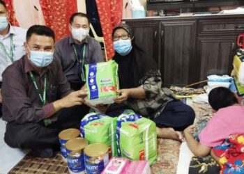 ZAMZURI Mansor (depan) menyerahkan sumbangan lampin pakai buang dan susu formula kepada Faridah Said di Kepala Batas, Pulau Pinang untuk kegunaan Noraihan Razali yang terlantar di atas tilam sejak 21 tahun lalu.